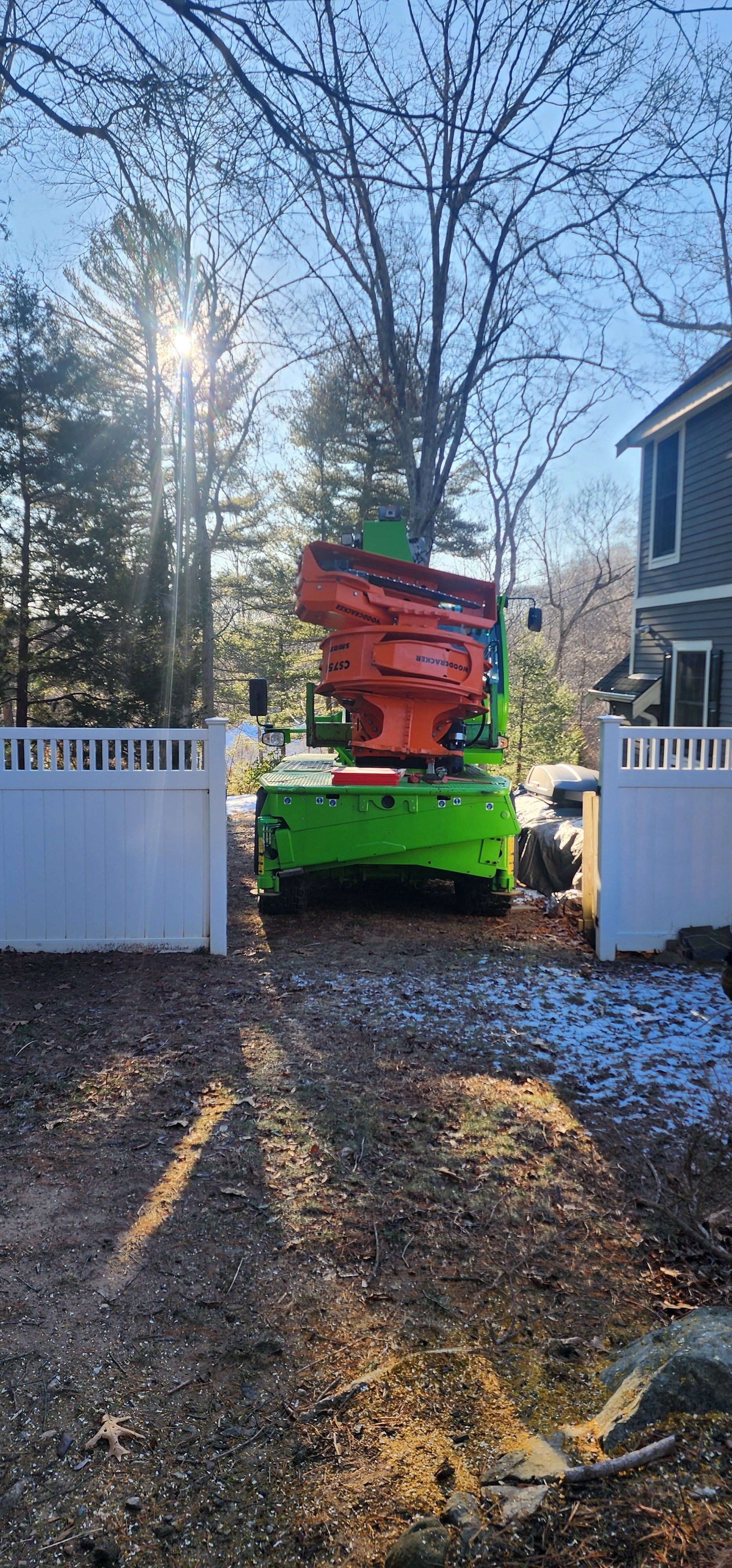 A green and orange machine is parked in a driveway in front of a house.