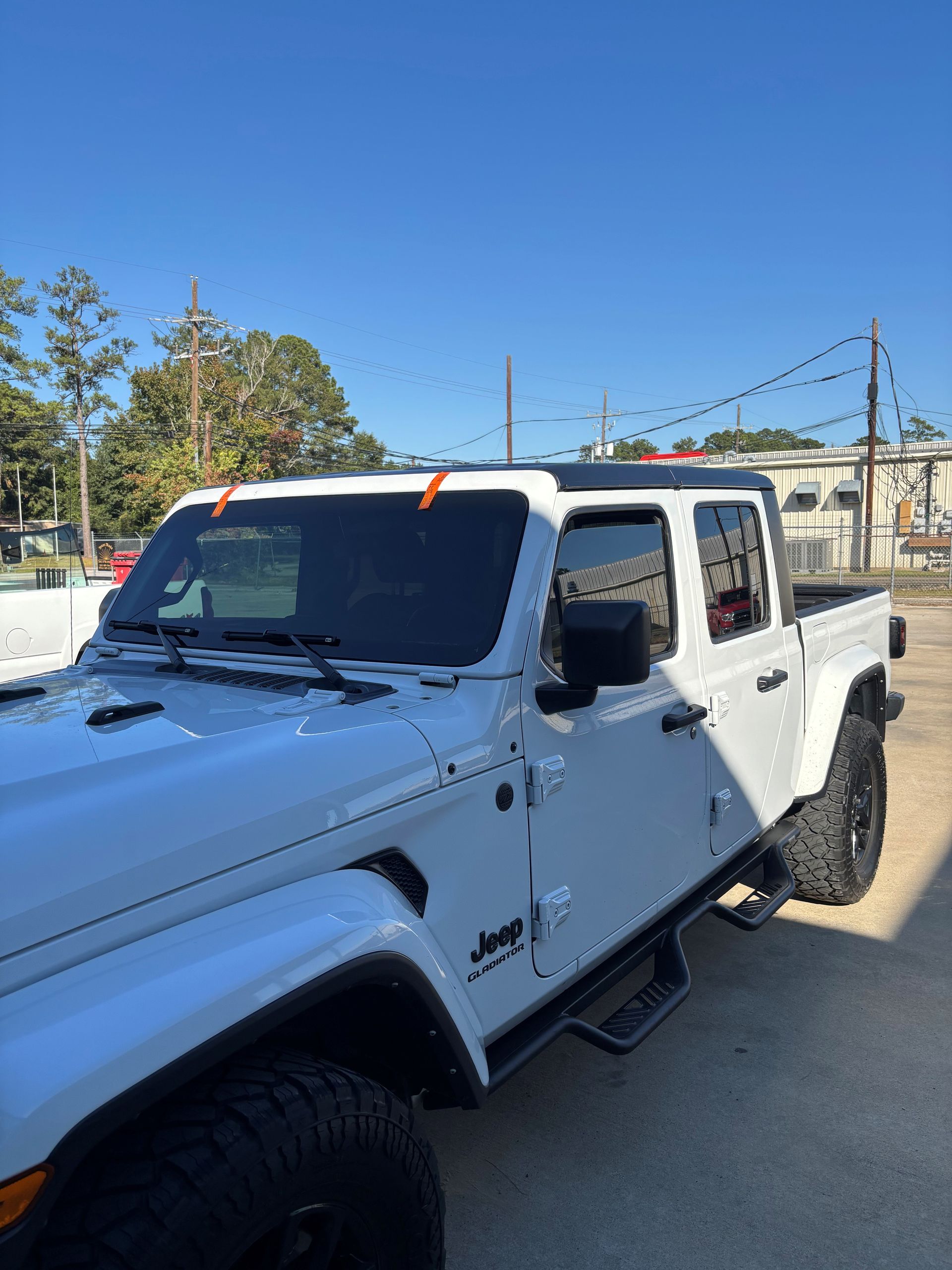A white Jeep Gladiator pickup truck parked outside on a sunny day.