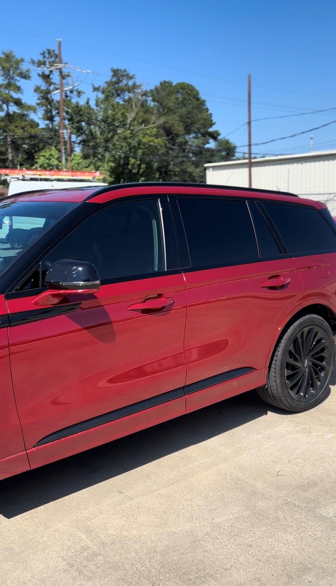 A red SUV with tinted windows and black rims parked on a sunny day.