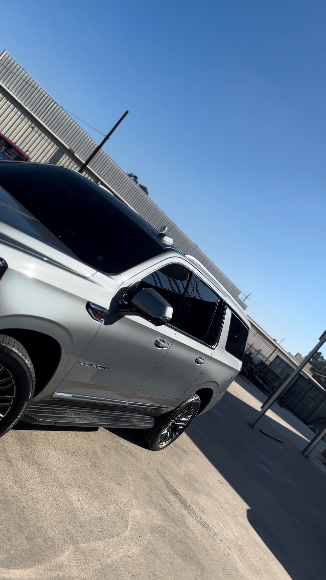 A silver SUV is parked in a paved outdoor lot under a clear blue sky.