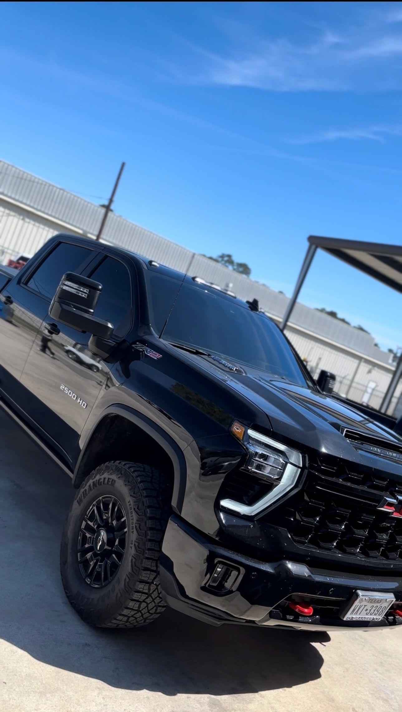 A black Chevrolet Silverado pickup truck parked on a sunny day in front of a white building.