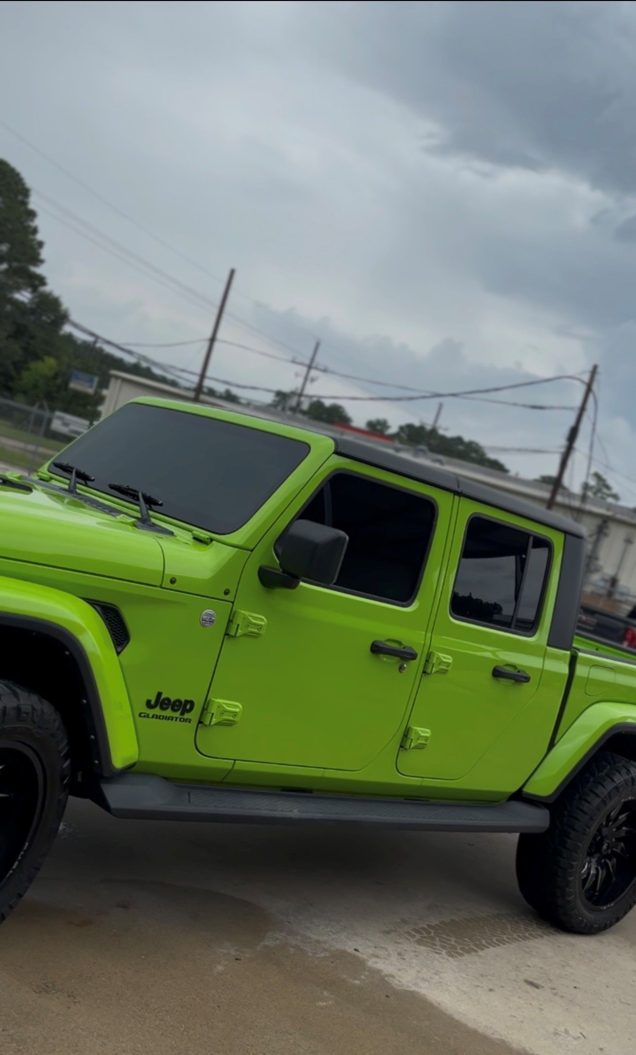 A lime green Jeep Gladiator pickup truck parked outside under a cloudy sky.