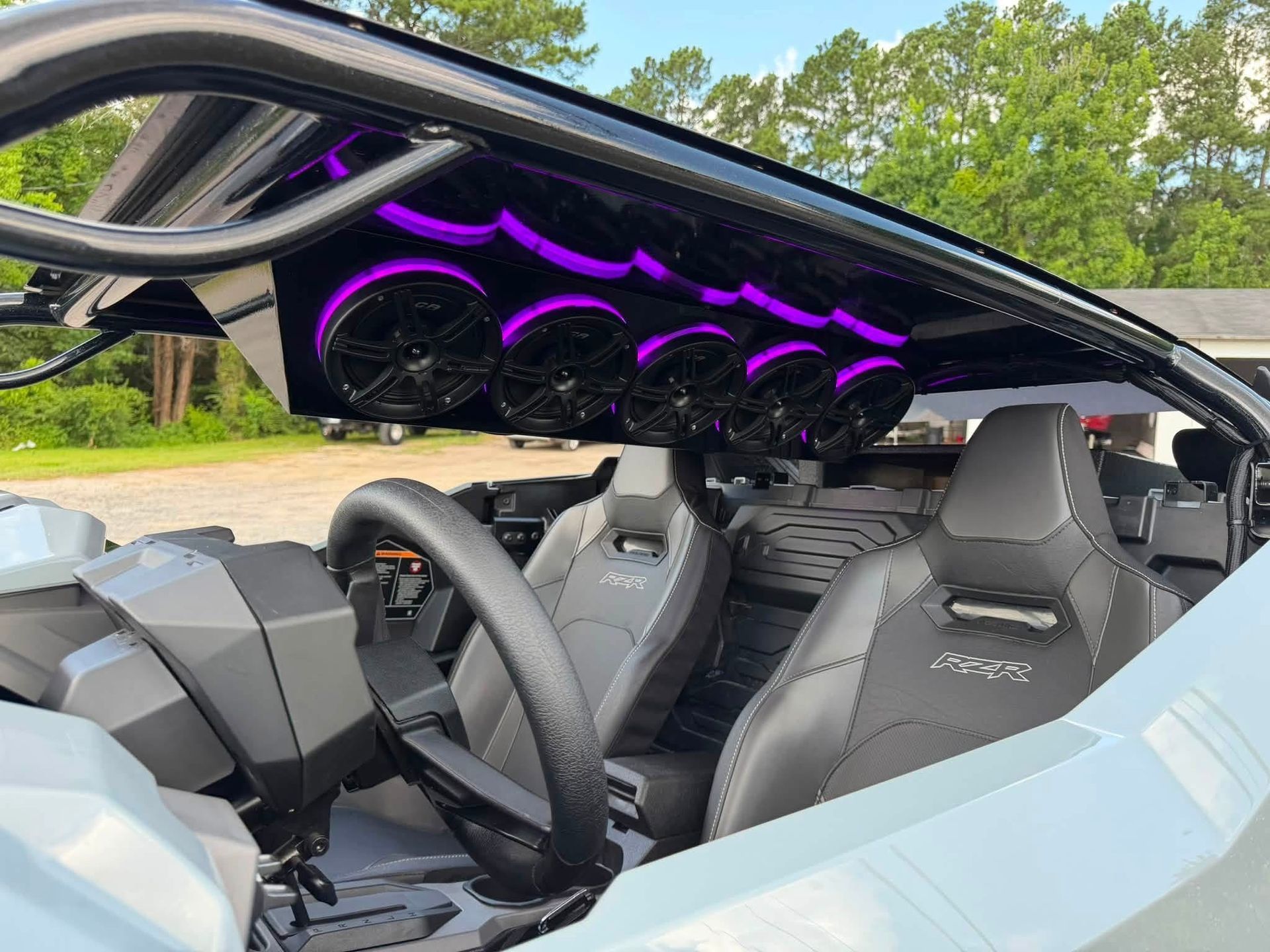 Luxury sports car interior with purple LED lighting and open roof, viewed from the driver’s seat