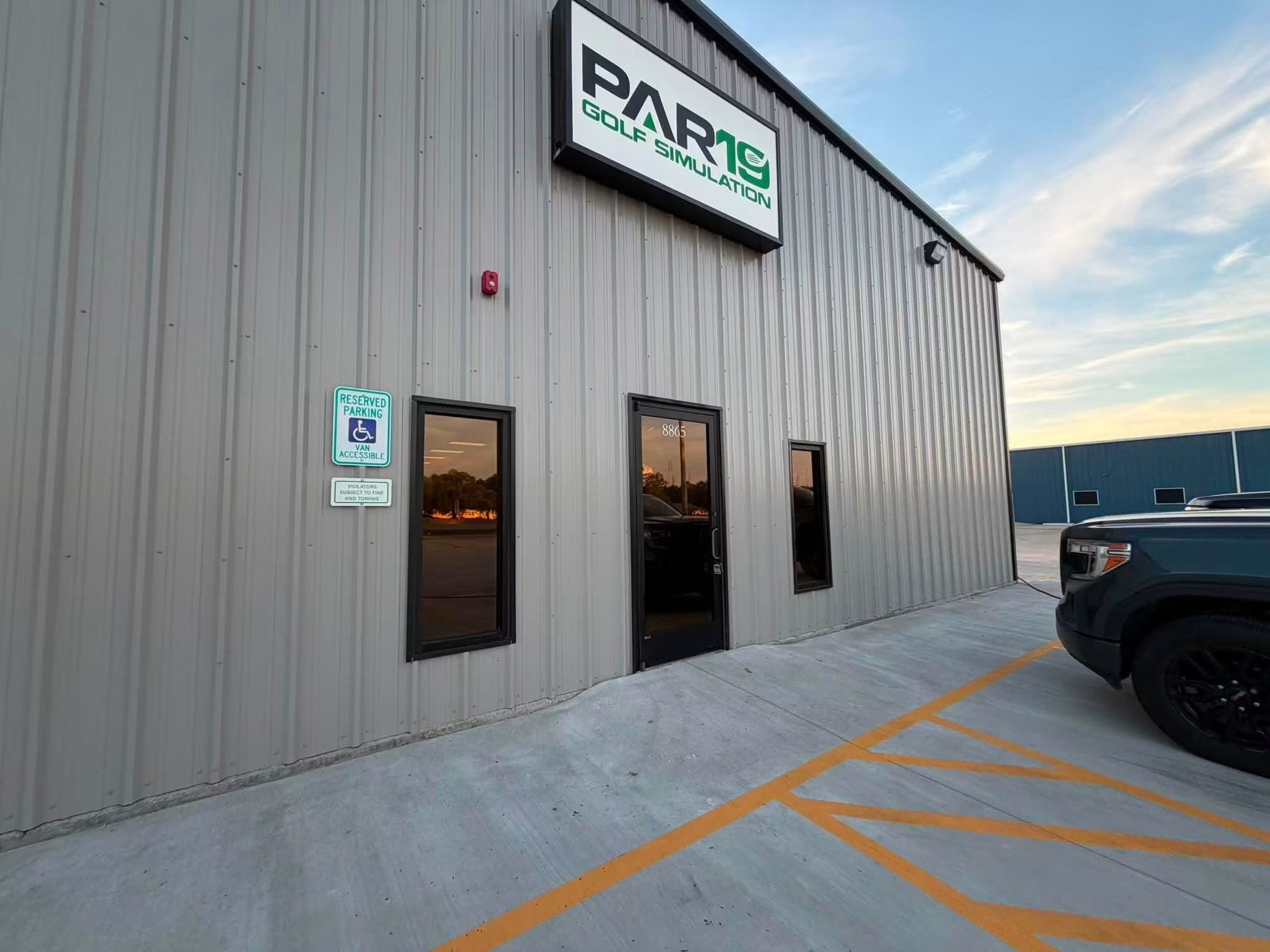 Exterior of PARIS building with gray siding and parked black SUV at dusk