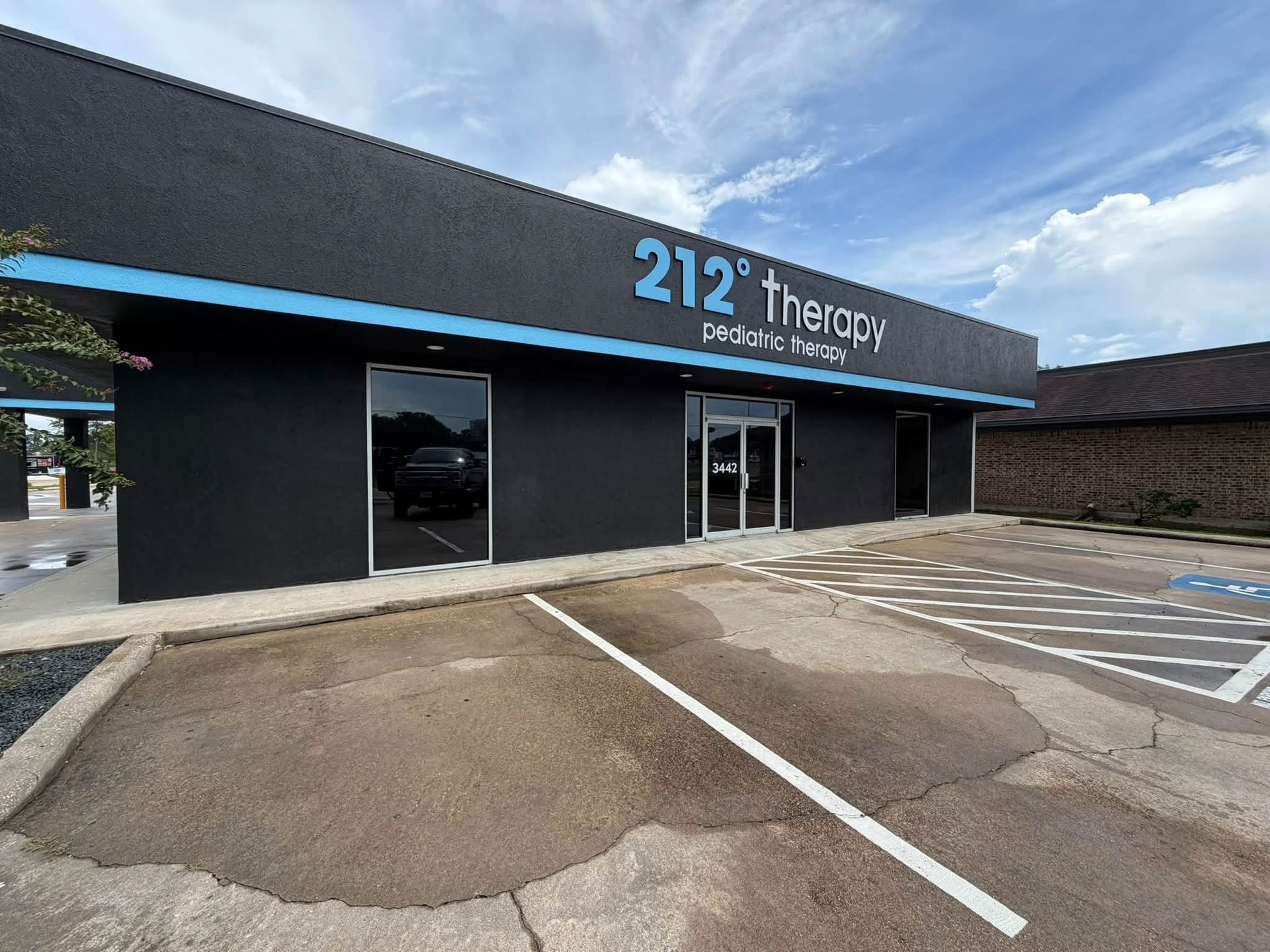 Front view of 212 Therapy storefront with glass doors, blue awning, and empty parking lot