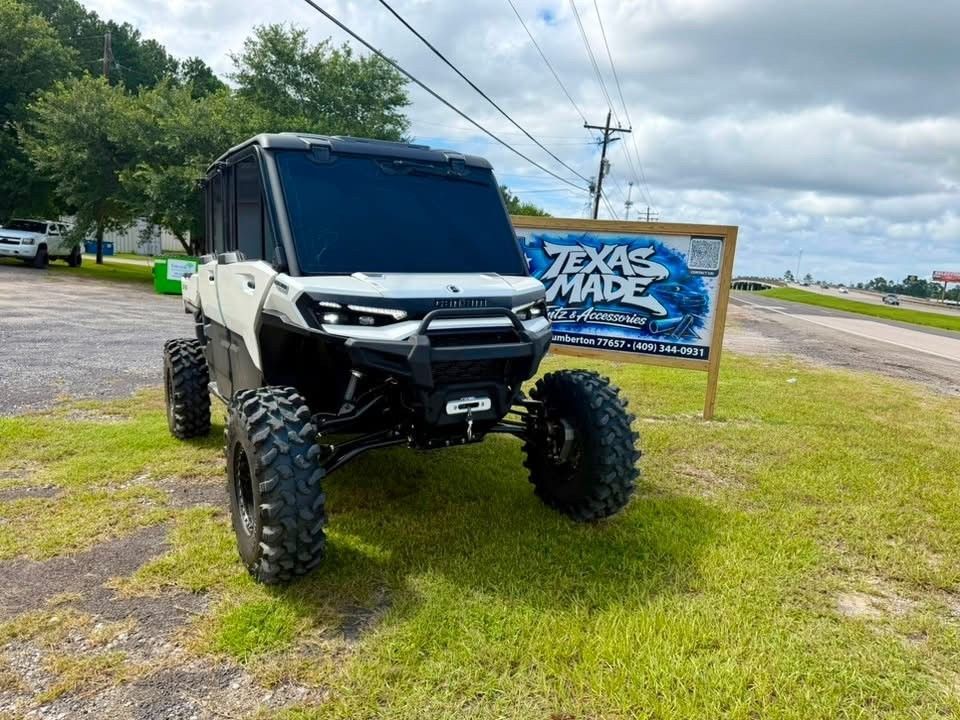 Black lifted off-road utility vehicle parked on grass beside a Texas Made sign under a cloudy sky