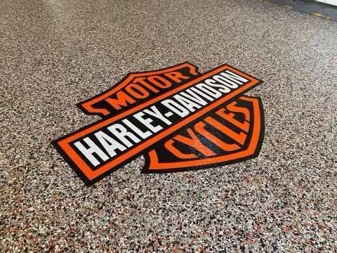 Harley-Davidson logo embedded in a speckled epoxy garage floor.