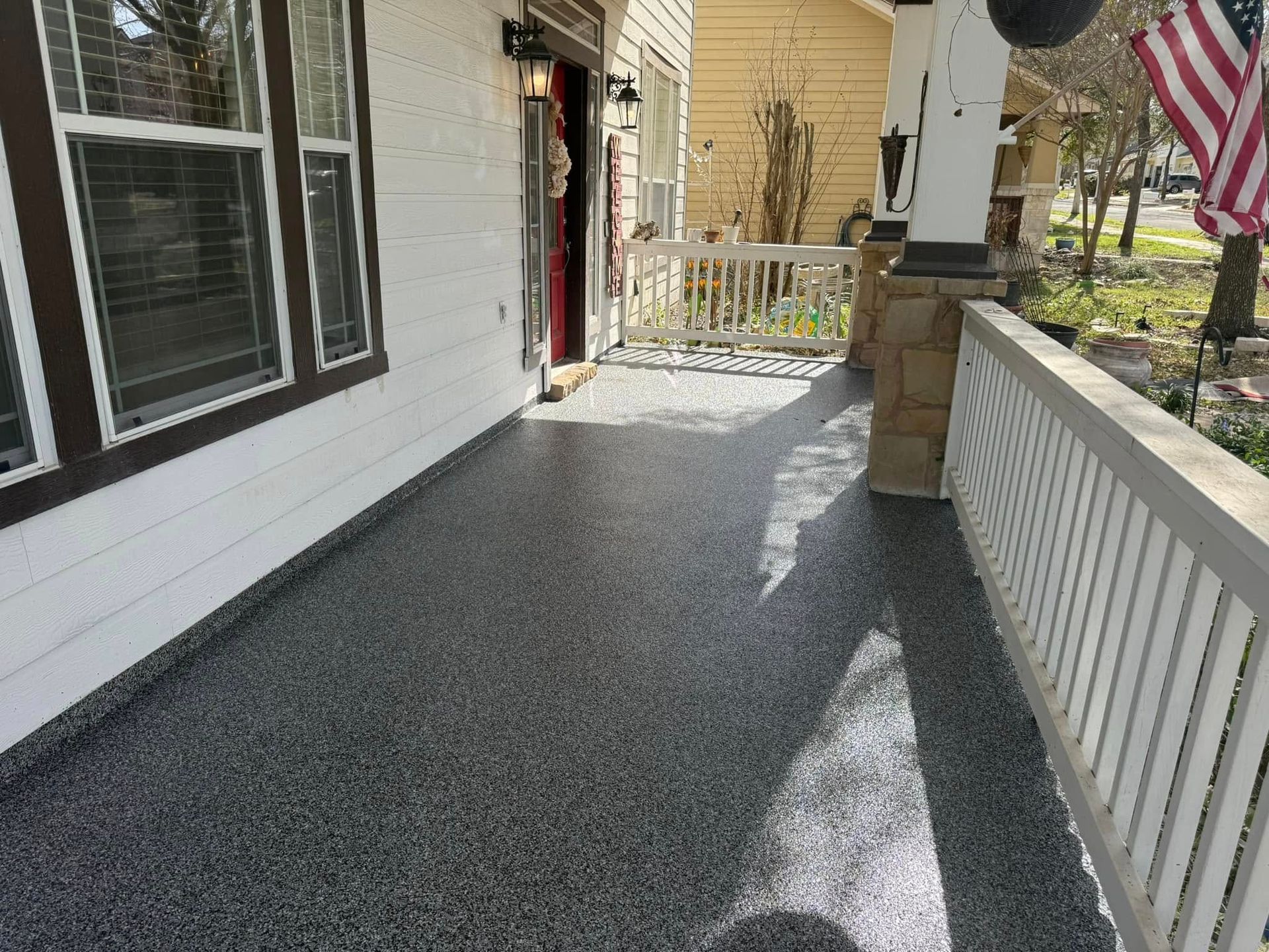 Gray epoxy-coated porch floor with white siding and railings, leading to a door and street view.