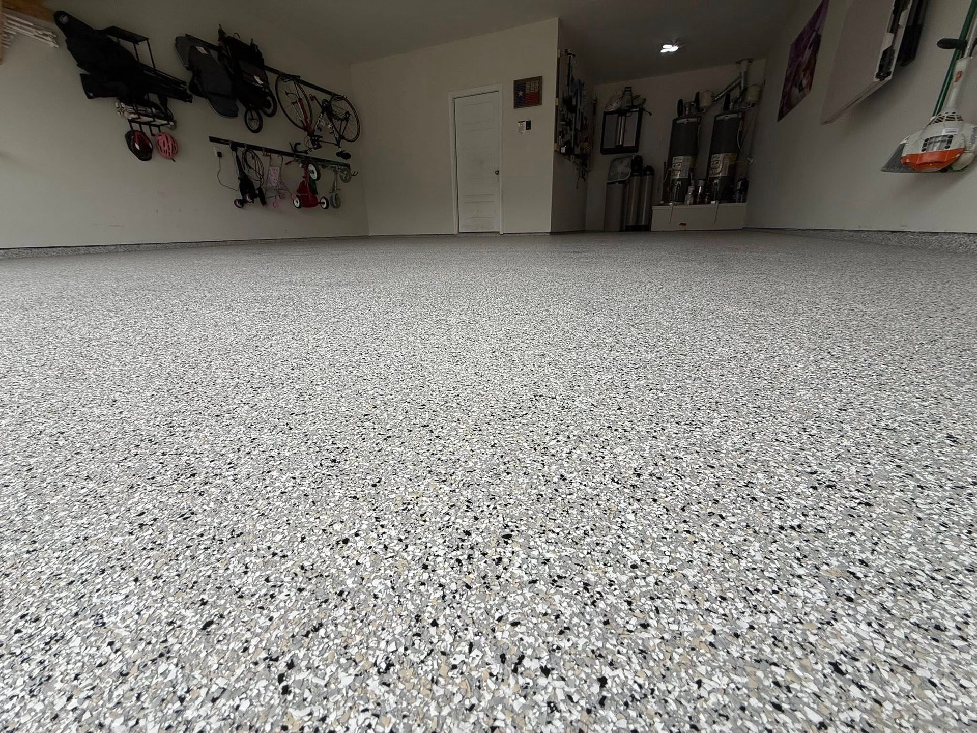 Garage floor with speckled epoxy coating. White walls and storage racks.