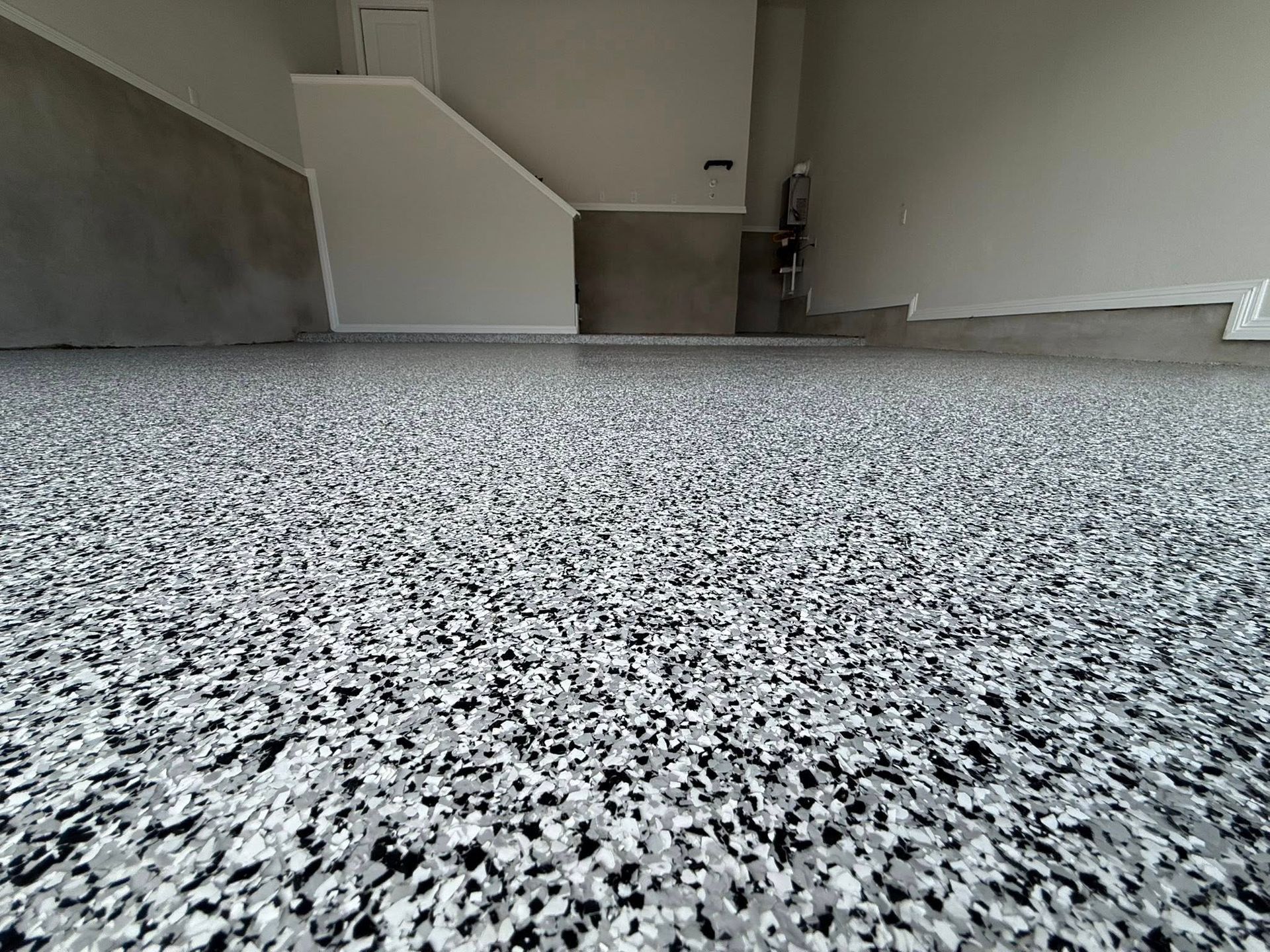 Garage floor with a speckled epoxy coating in shades of gray and white.