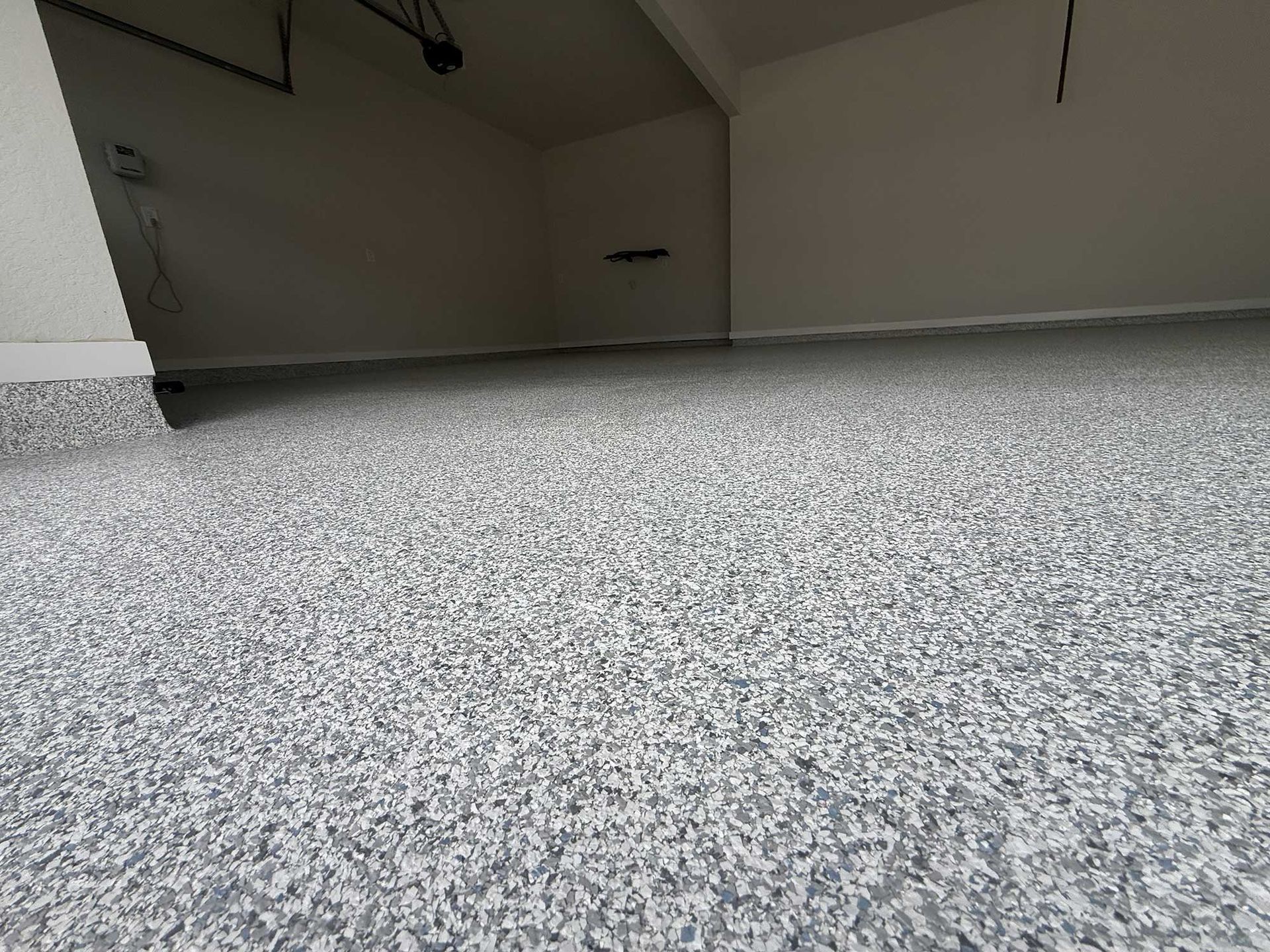 Garage with a speckled gray epoxy floor. White walls, empty space.