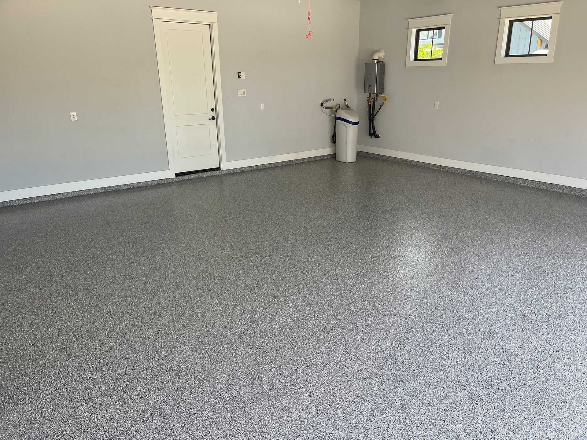 Garage with speckled gray epoxy floor, white door and trim, gray walls, and two windows.