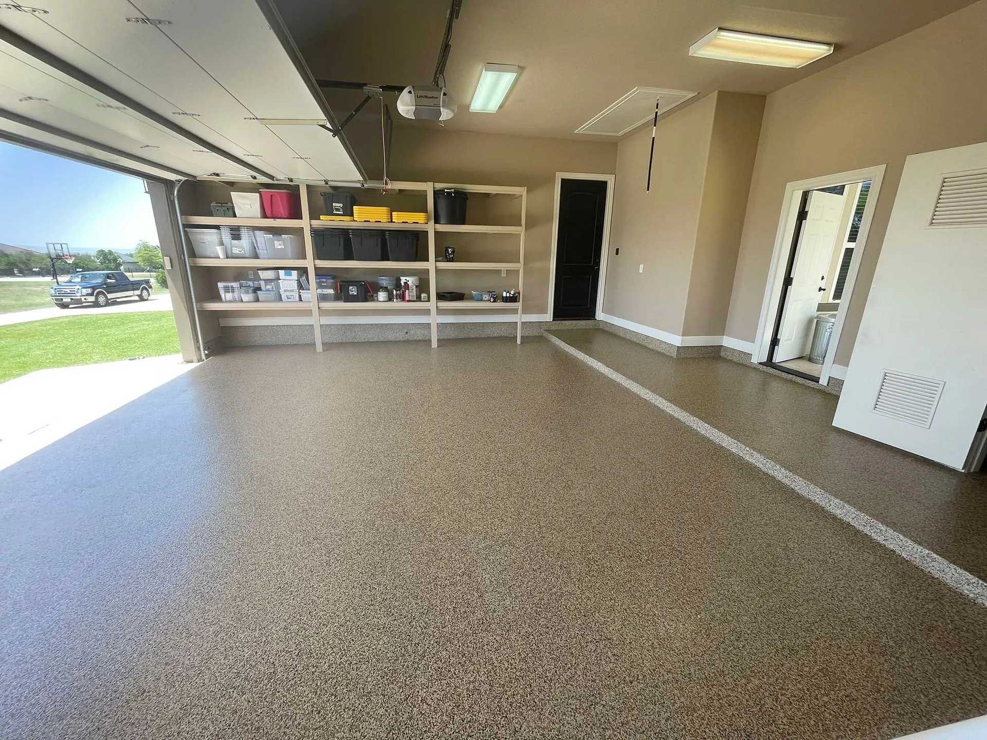 Covered patio with stone wall and speckled floor; grass and sky visible in the background.
