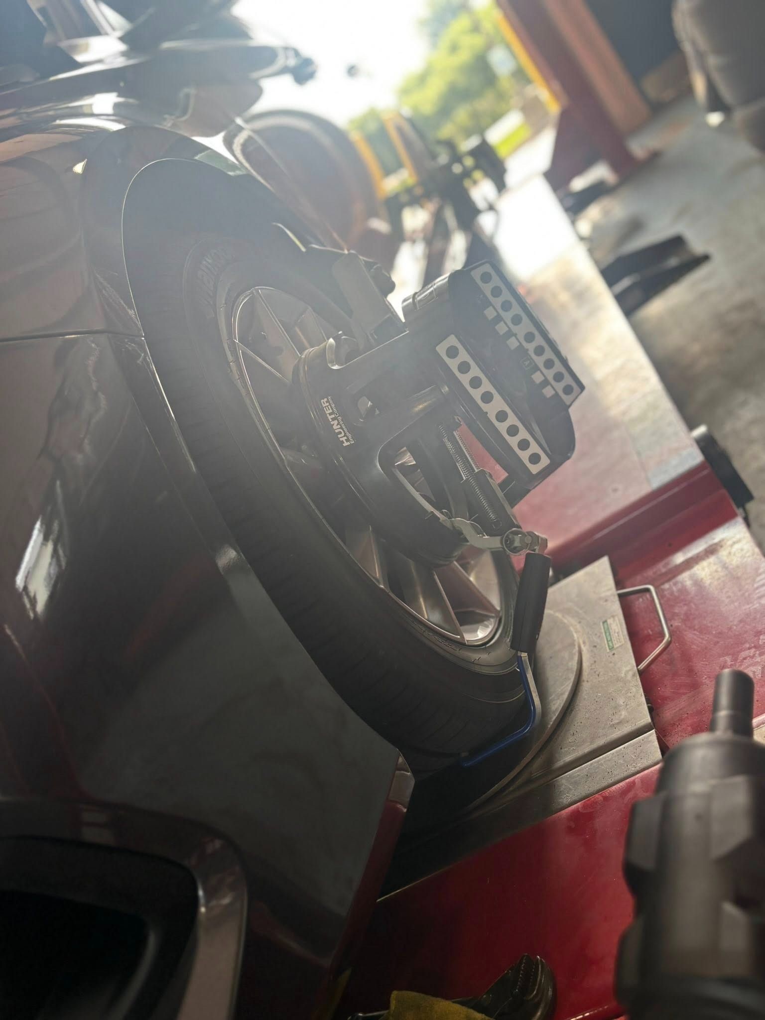 Car tire on a lift being aligned, with sensors attached. The setting is a garage.
