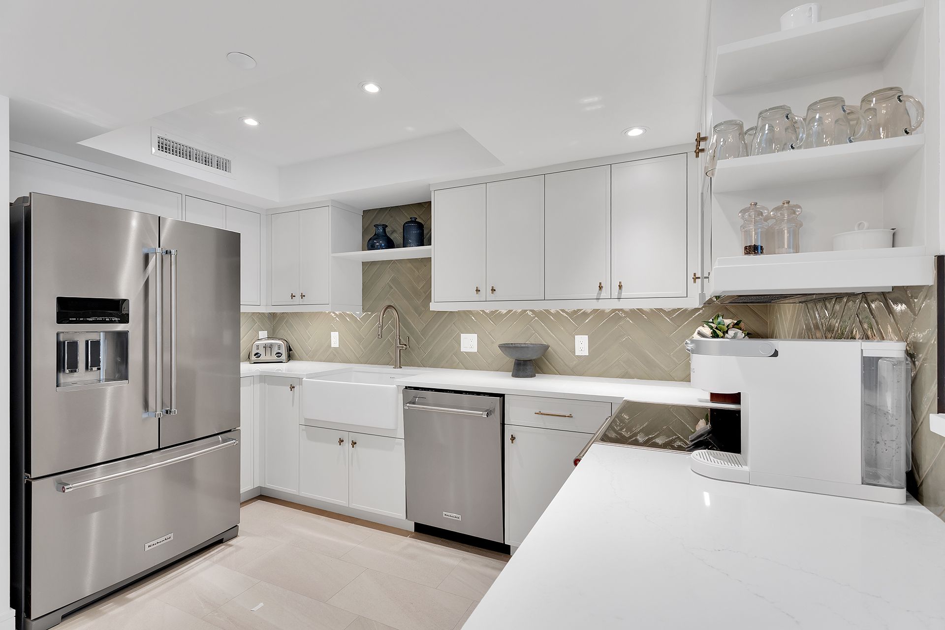 Bright modern white kitchen with stainless steel appliances, gray backsplash, and island counter