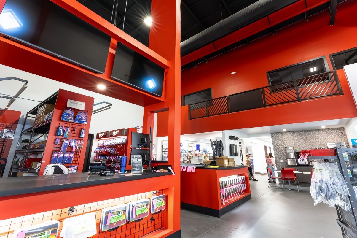 Bright red retail store interior with clothing racks and checkout counters under black ceilings