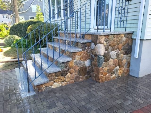 Stone steps with metal handrails leading to a house entrance.