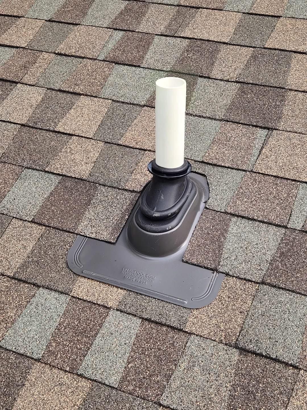 Roof vent pipe with black flashing on a shingled roof