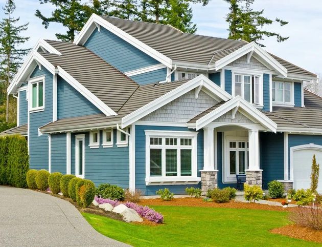 Blue two-story suburban house with white trim, stone accents, and a landscaped front yard