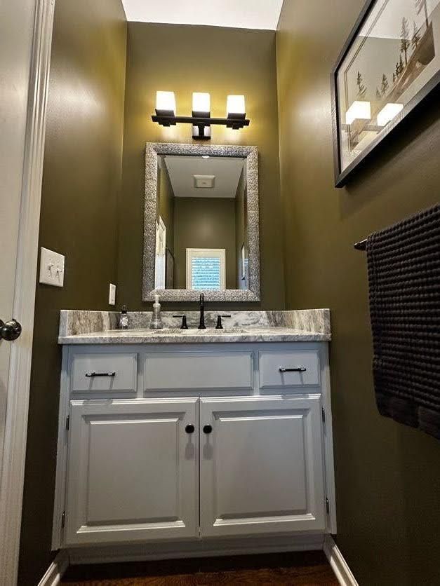 A bathroom with a sink, mirror and towel rack.
