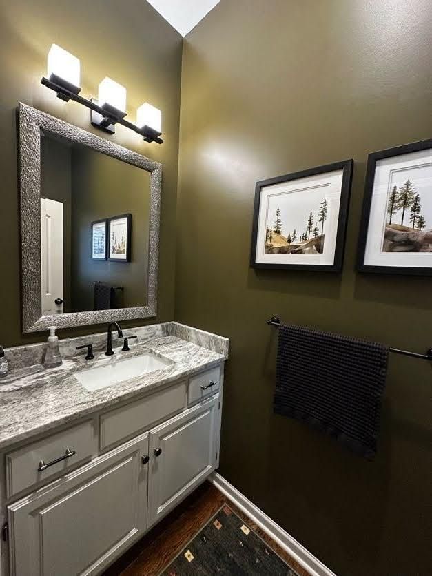 A bathroom with a sink, mirror and two pictures on the wall.