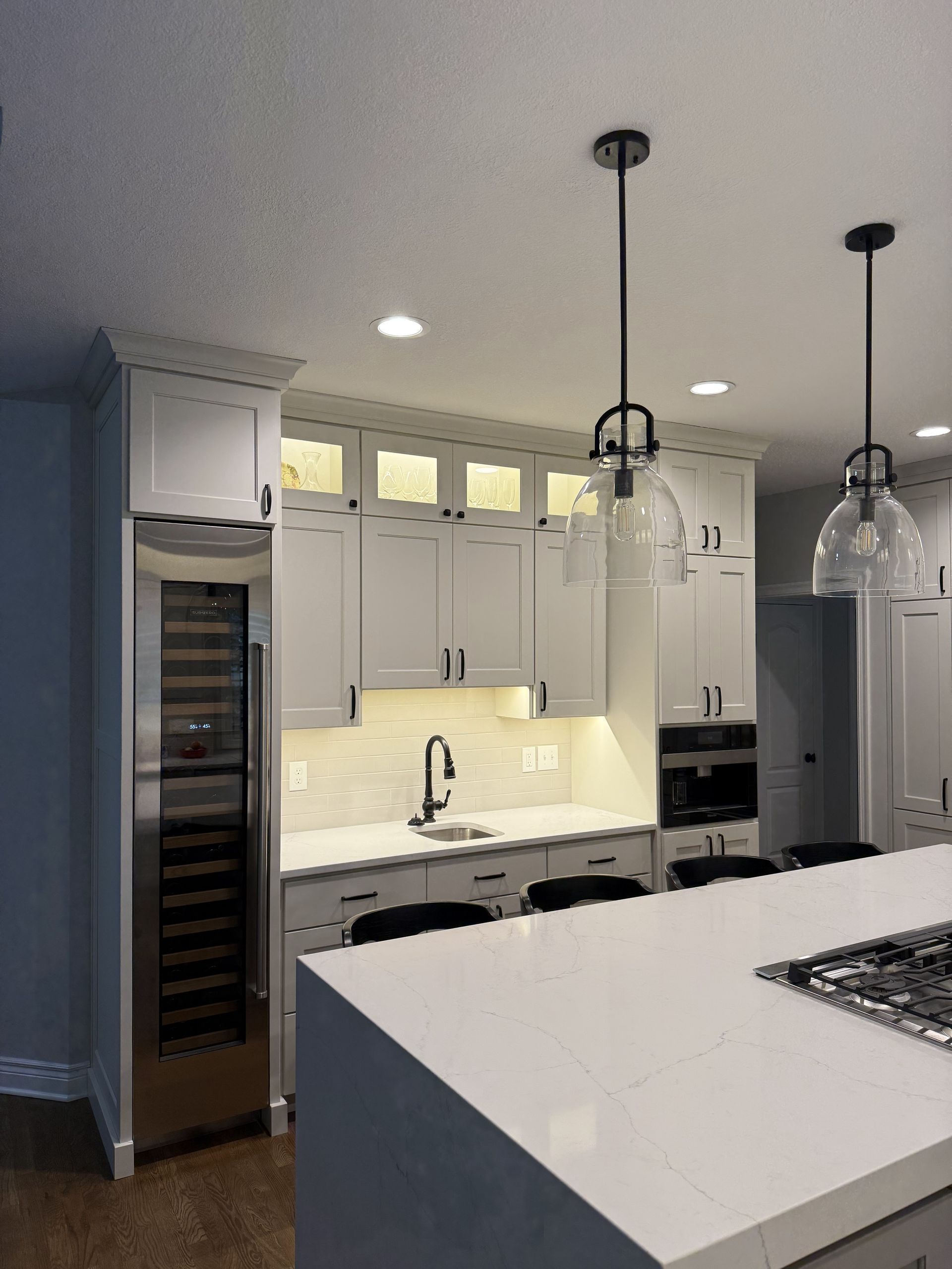 A kitchen with white cabinets and a wine cooler