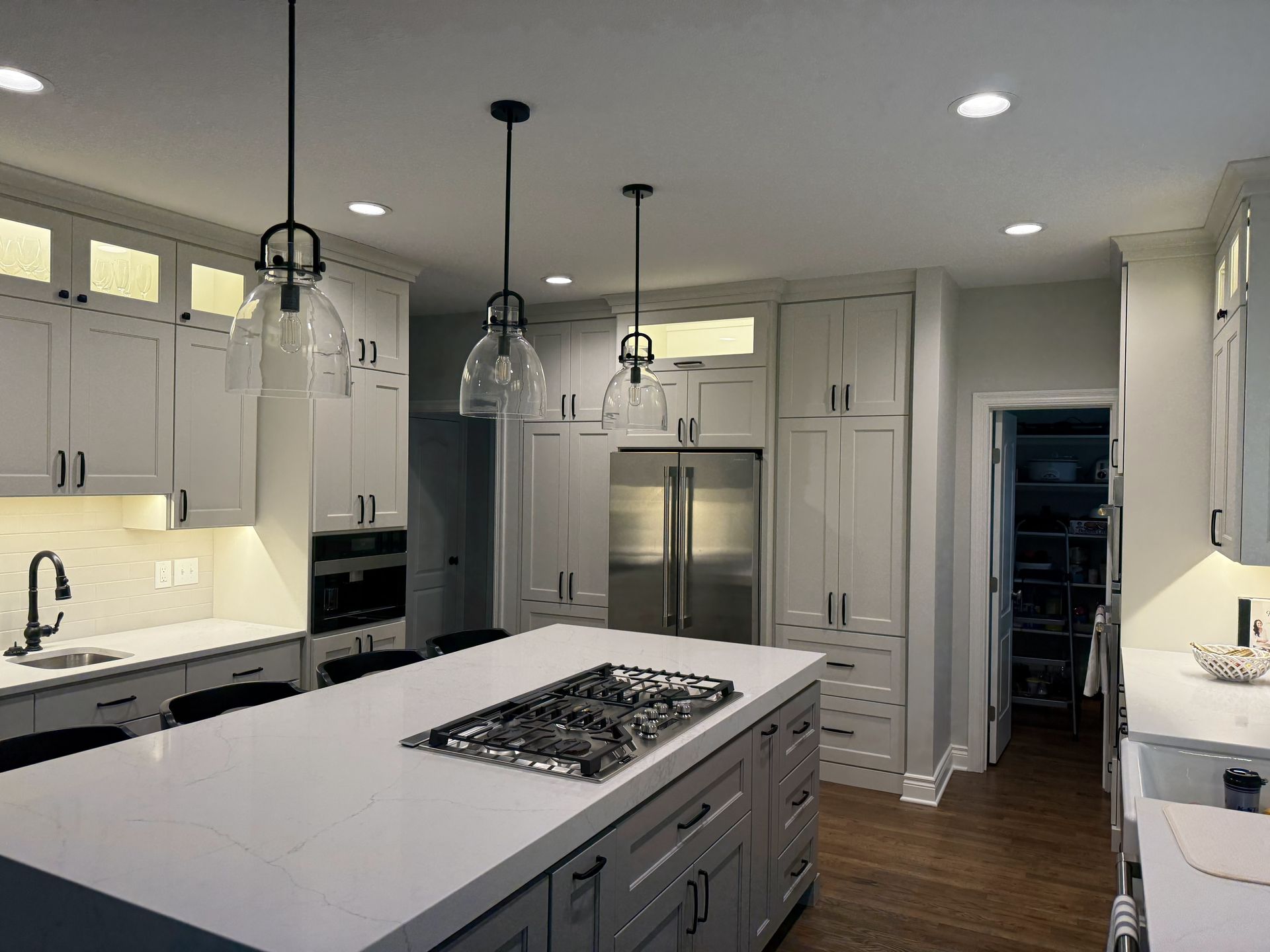 A kitchen with white cabinets and a large island with a stove top oven.