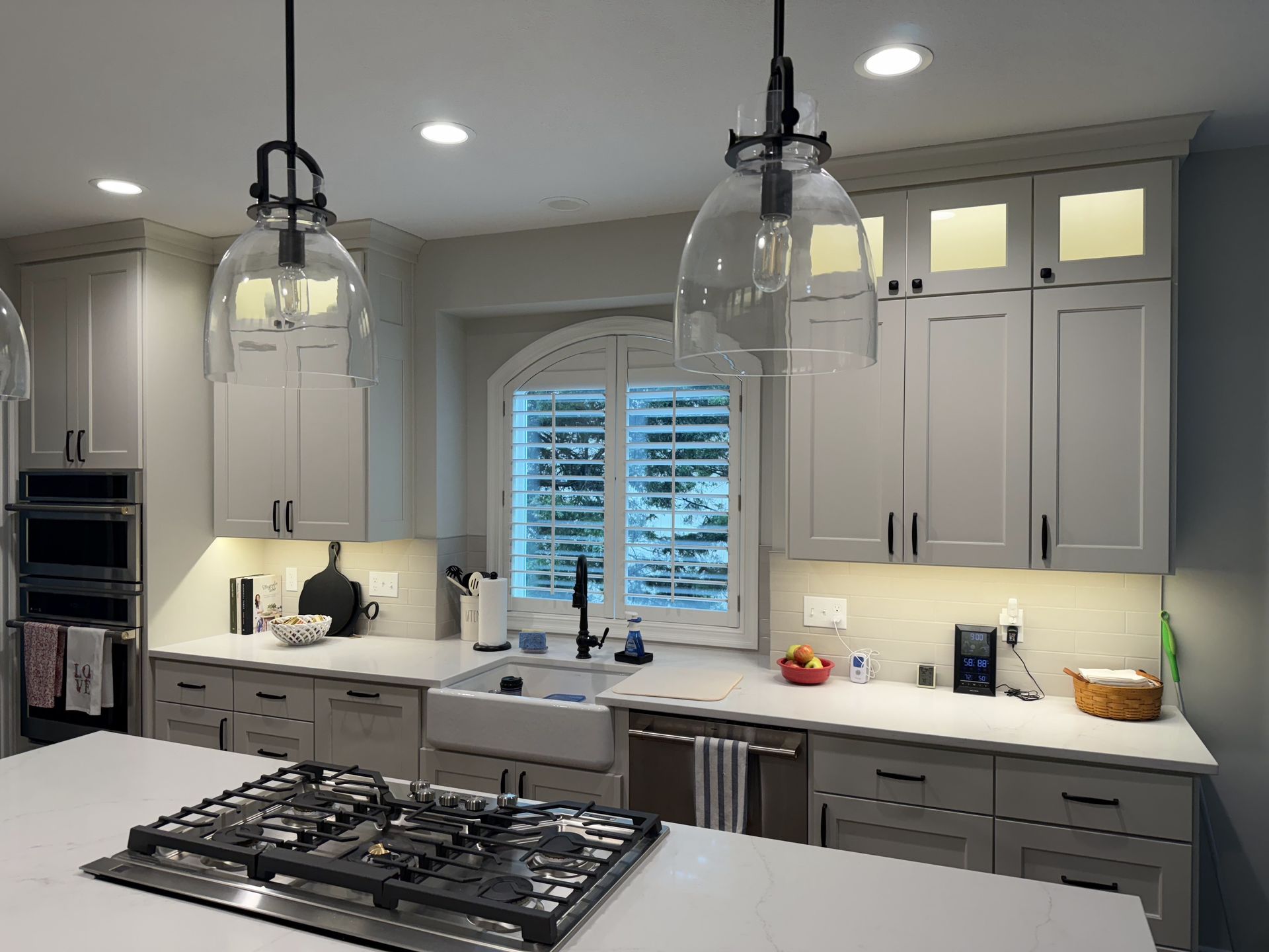 A kitchen with white cabinets, a stove top oven, a sink and a window.