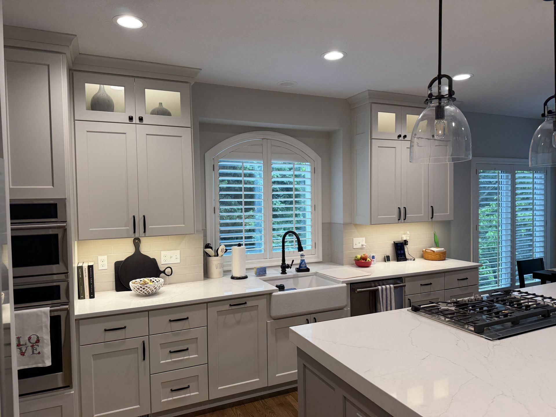 A kitchen with white cabinets, a sink, a stove , and a window.