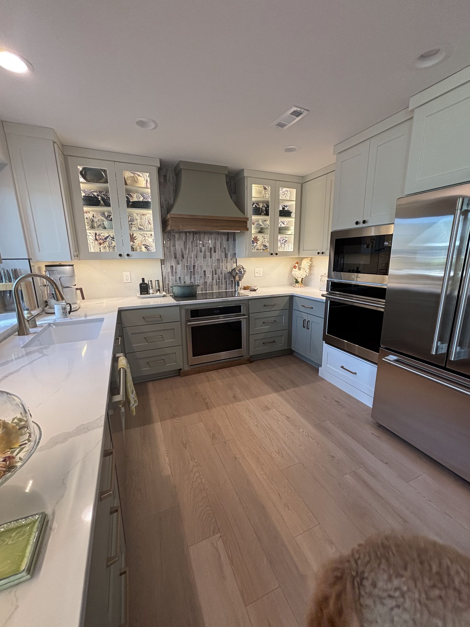 A kitchen with white cabinets, stainless steel appliances, a sink, and a dog.