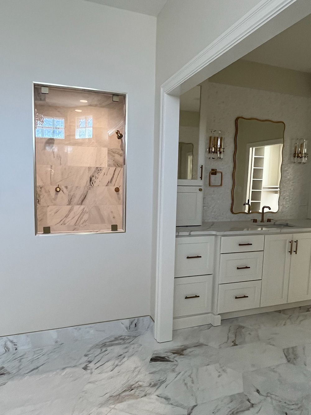Modern bathroom with marble flooring, vanity, mirror, and an open shower alcove.