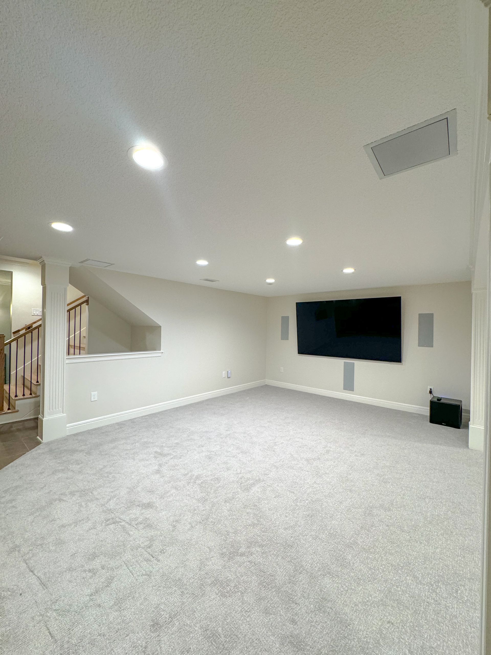 An empty basement with a flat screen tv on the wall.