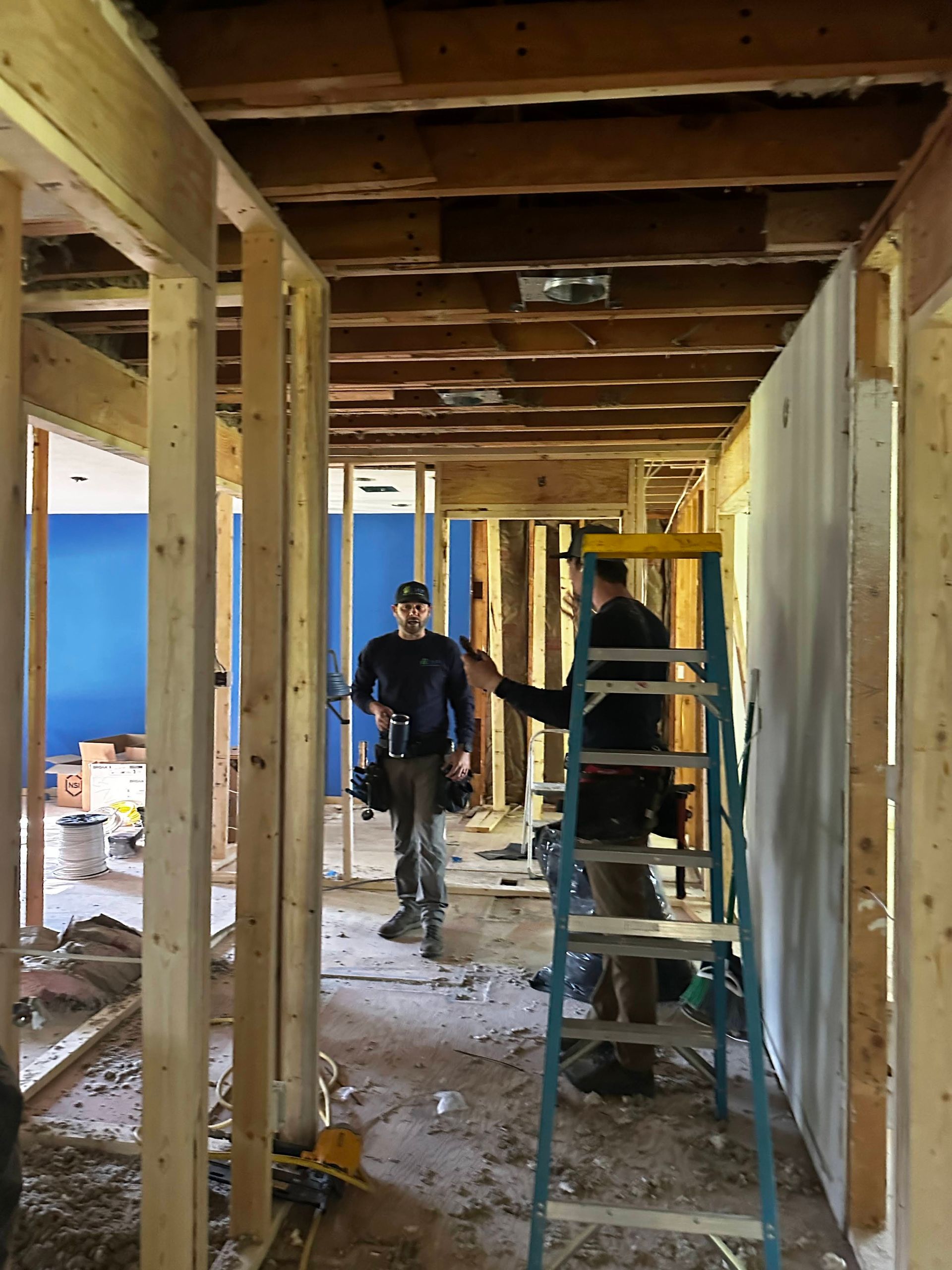 Two men are working on a wall in a house under construction.
