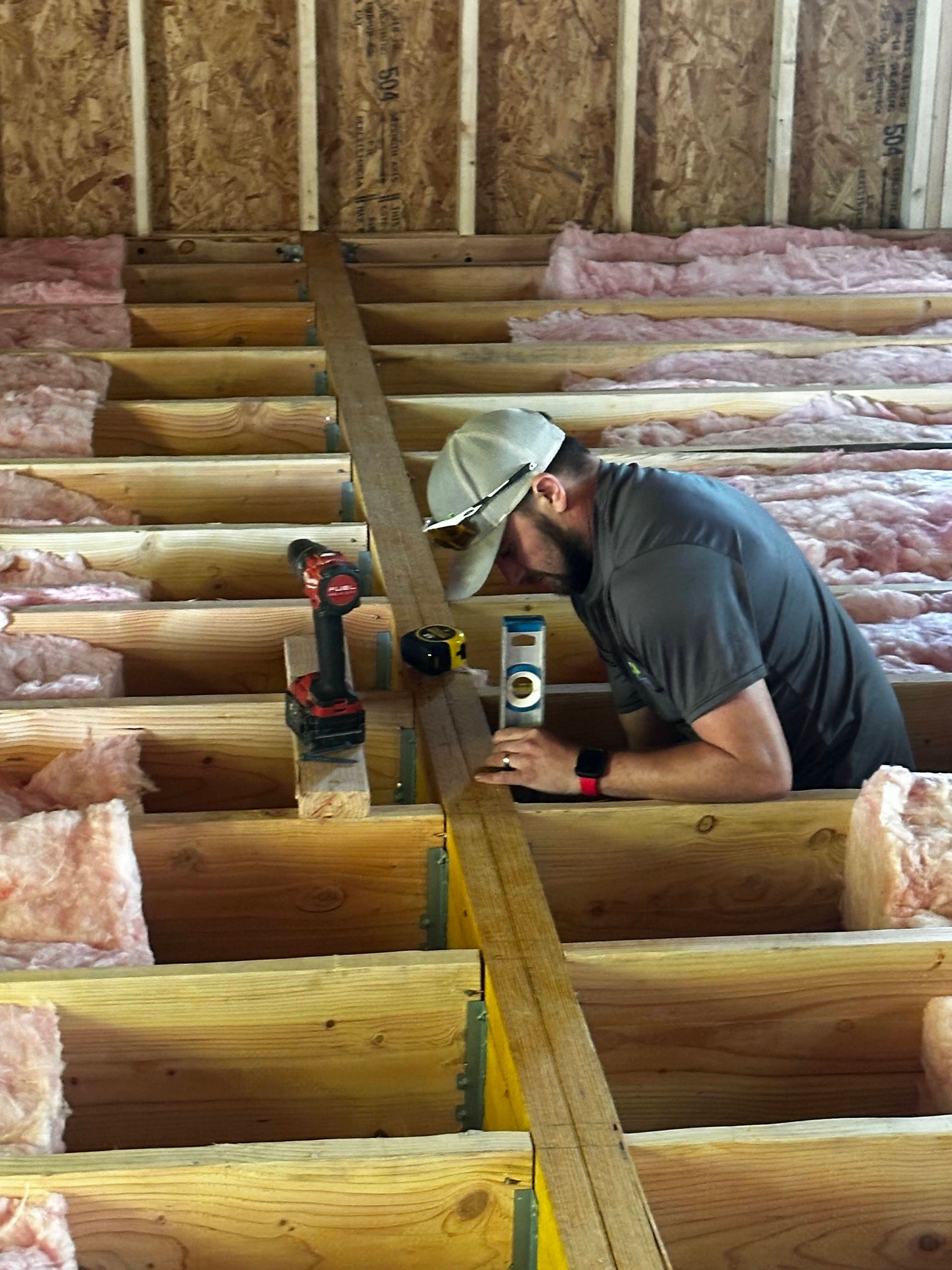 A man is measuring a piece of wood in a room.