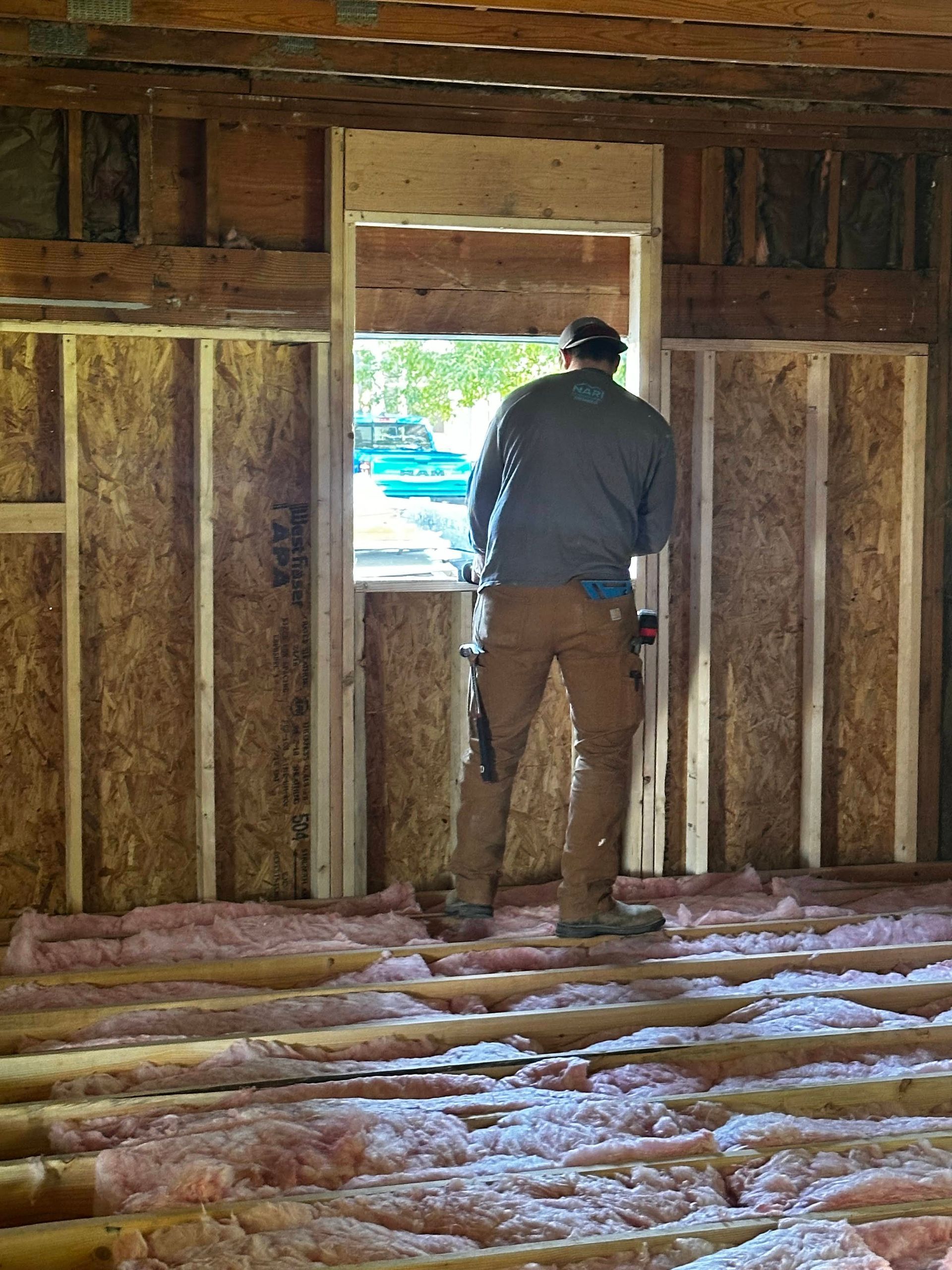 A man is standing in a room constructing the window.