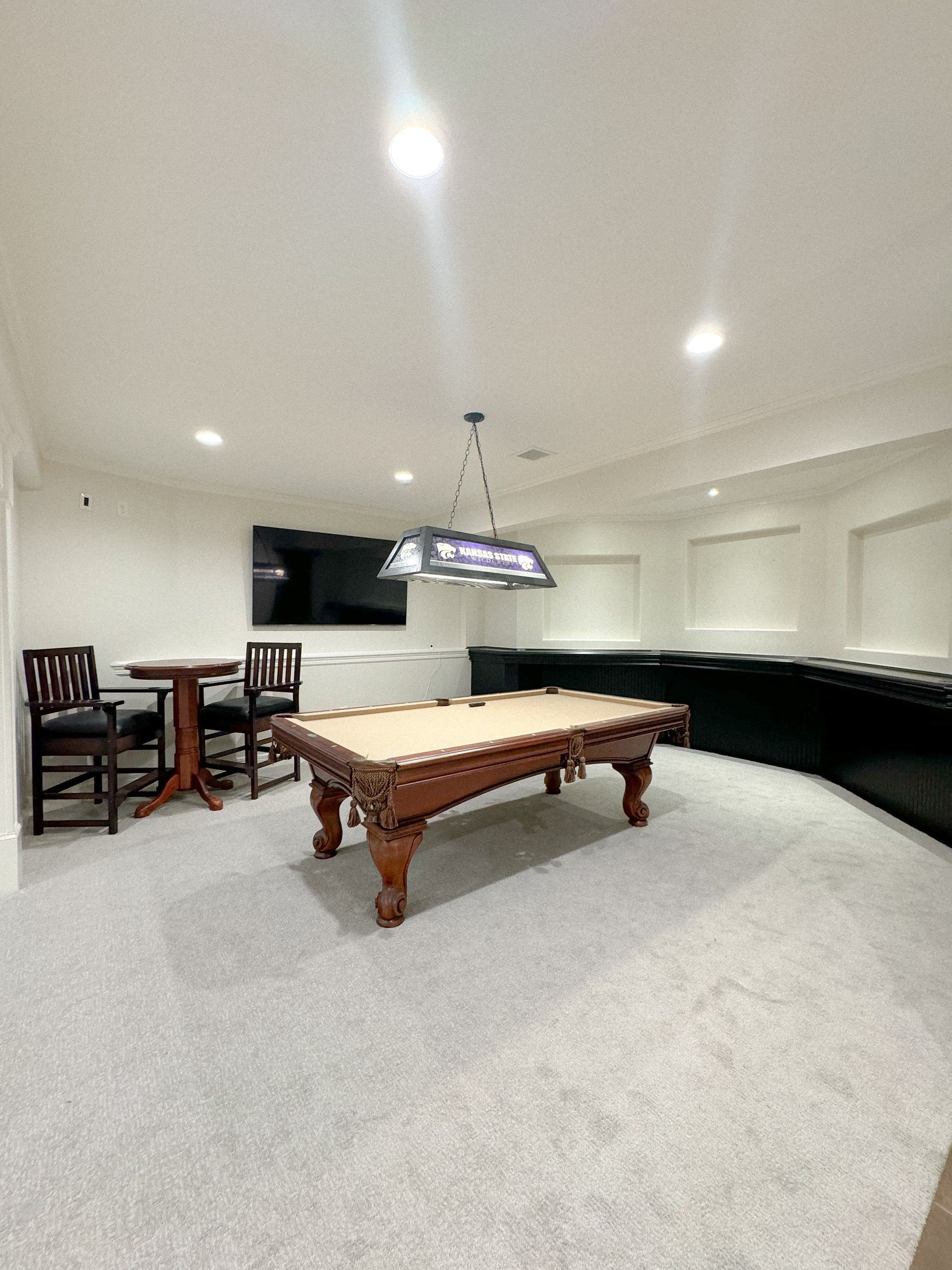 A billiard table, a table, and chairs in the basement.