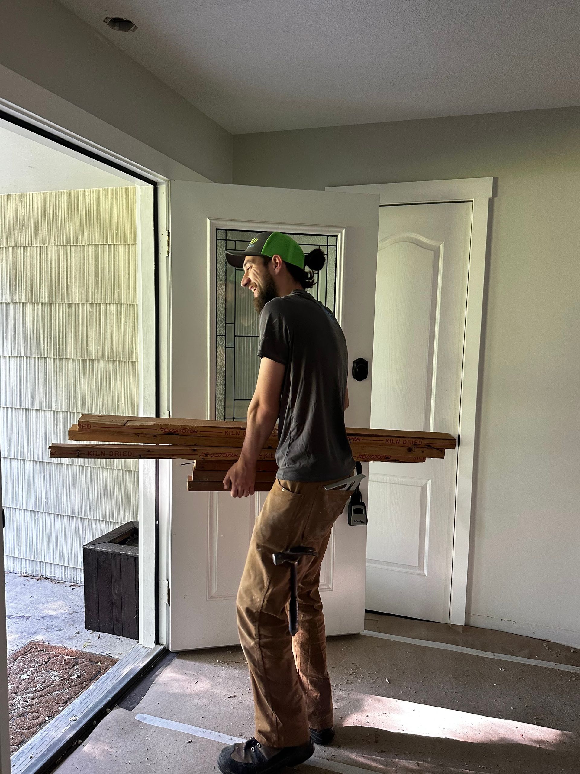A man is carrying a stack of wood in a room.