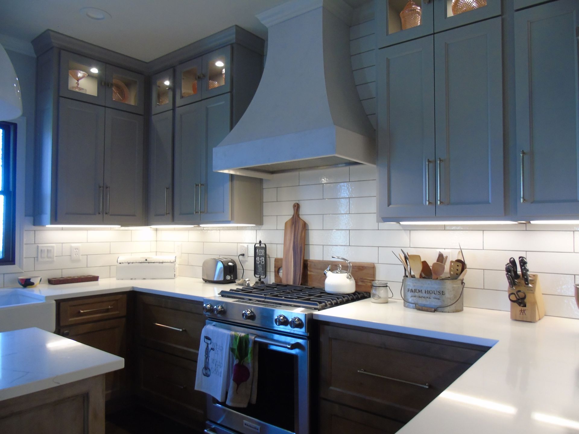 A kitchen with gray cabinets and white countertops.