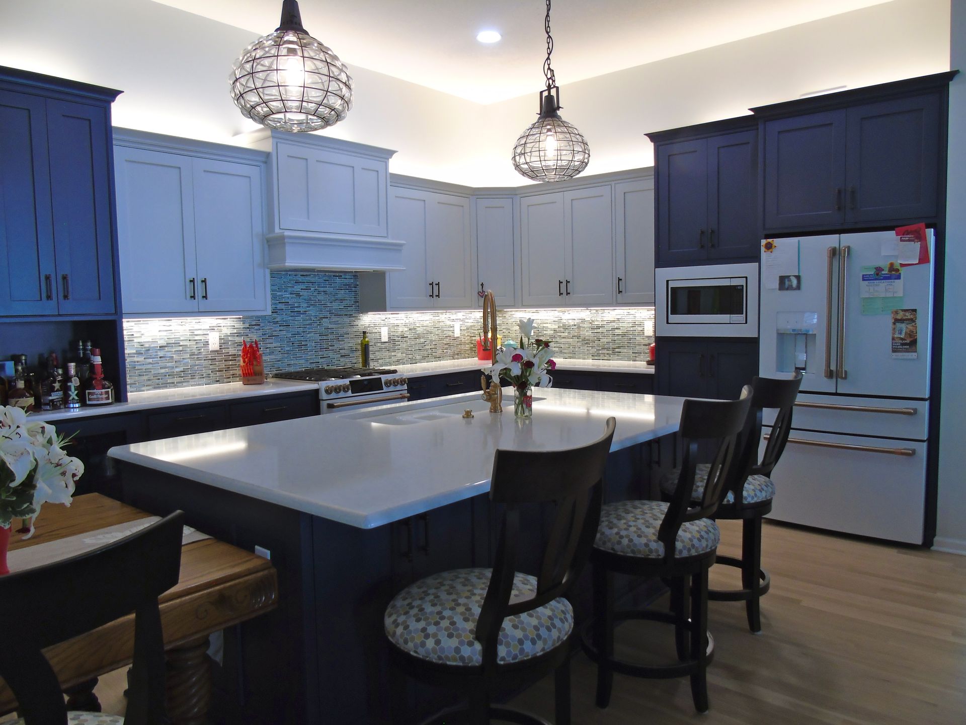 A kitchen with blue cabinets and white countertops, and a large island.