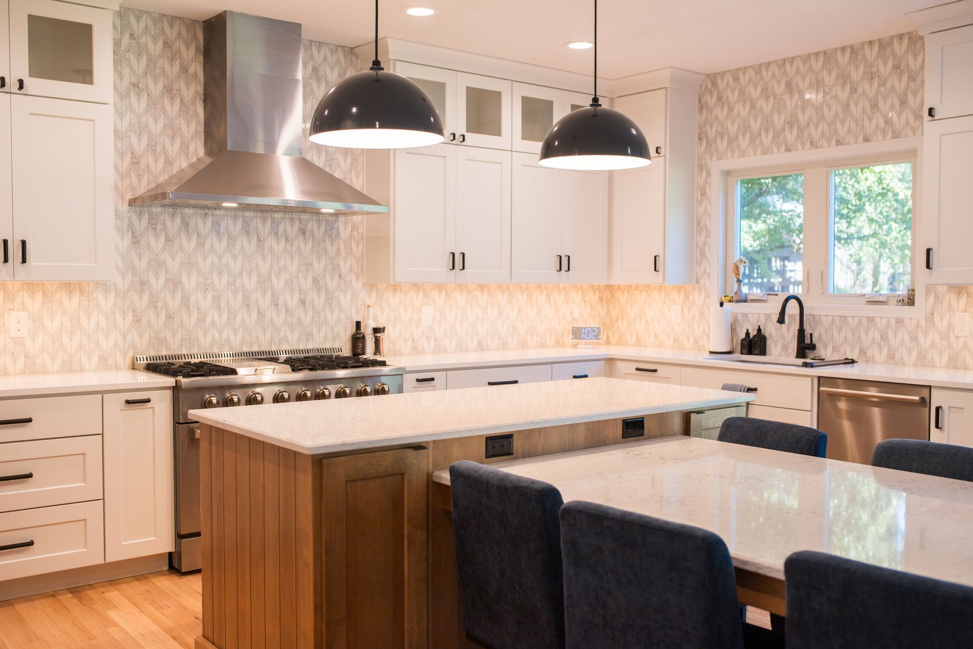 Modern kitchen with white cabinets, stainless steel appliances, and a wooden island with seating.