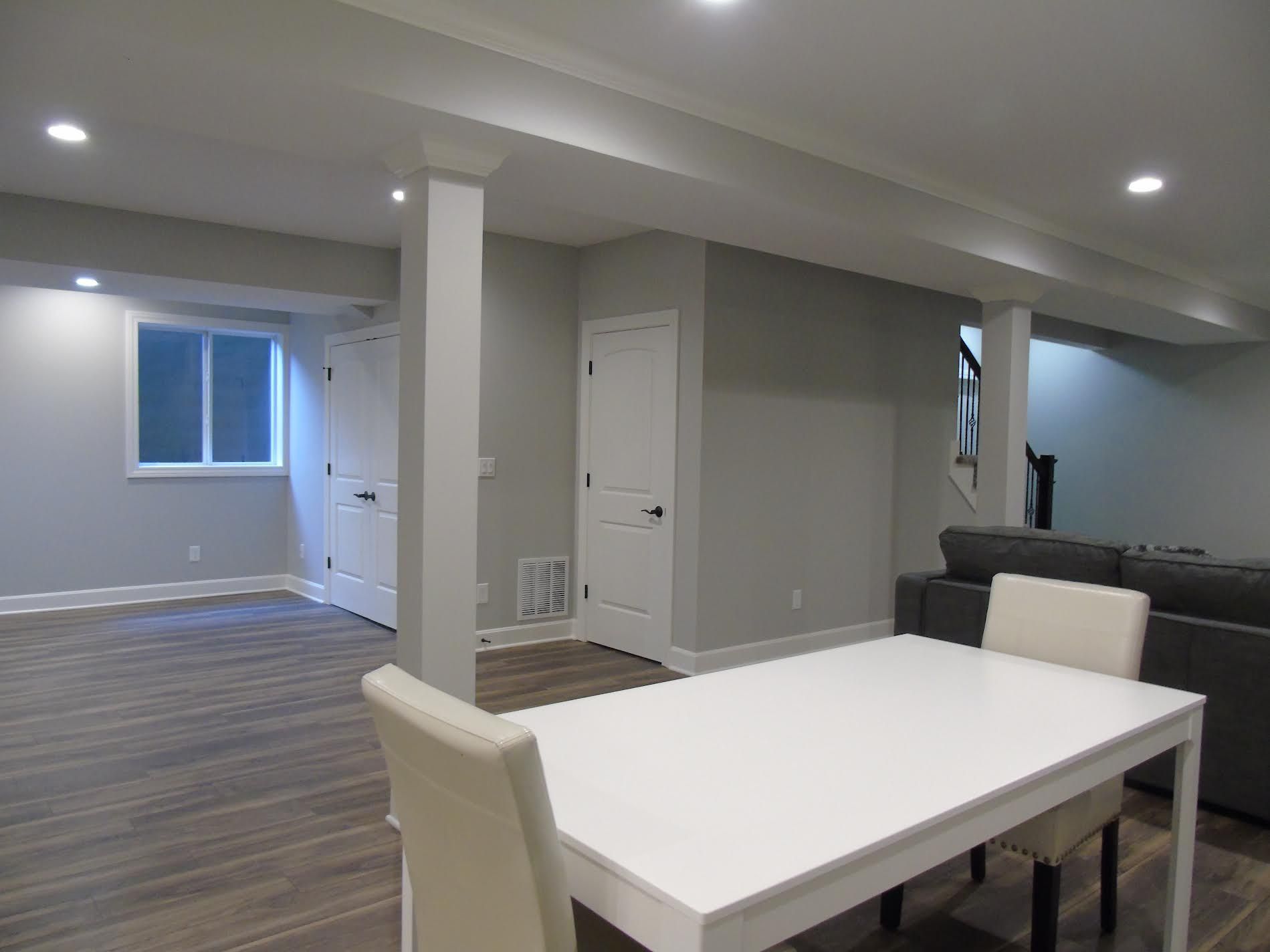 Empty, gray-painted basement room with white table and chairs