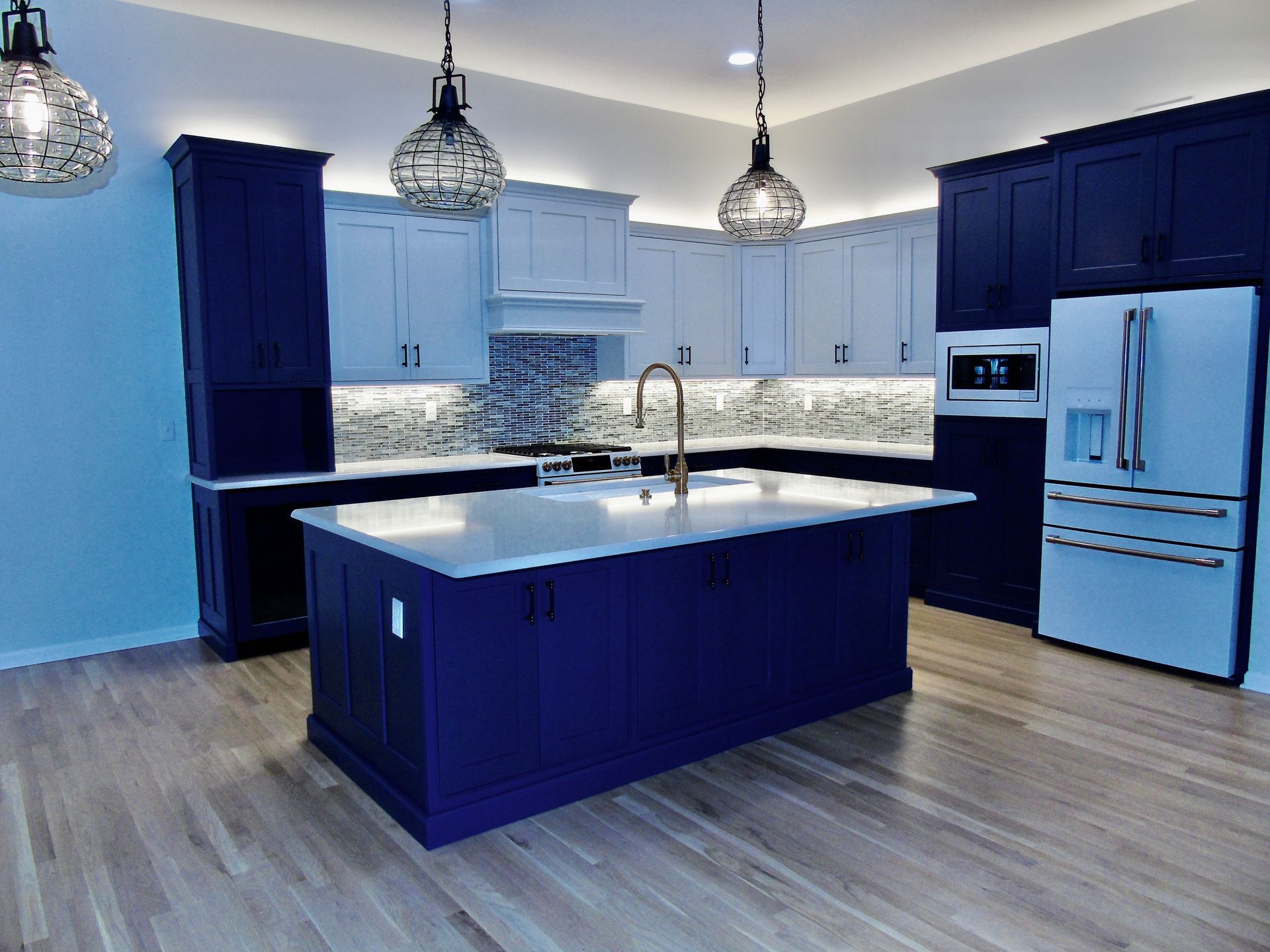 Modern kitchen with blue and white cabinets, island, and stainless steel appliances.