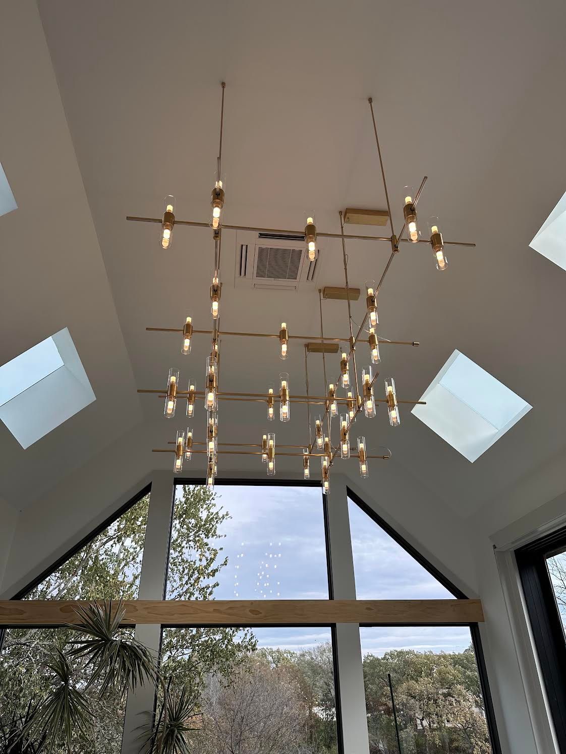 Modern gold chandelier hanging from a white vaulted ceiling
