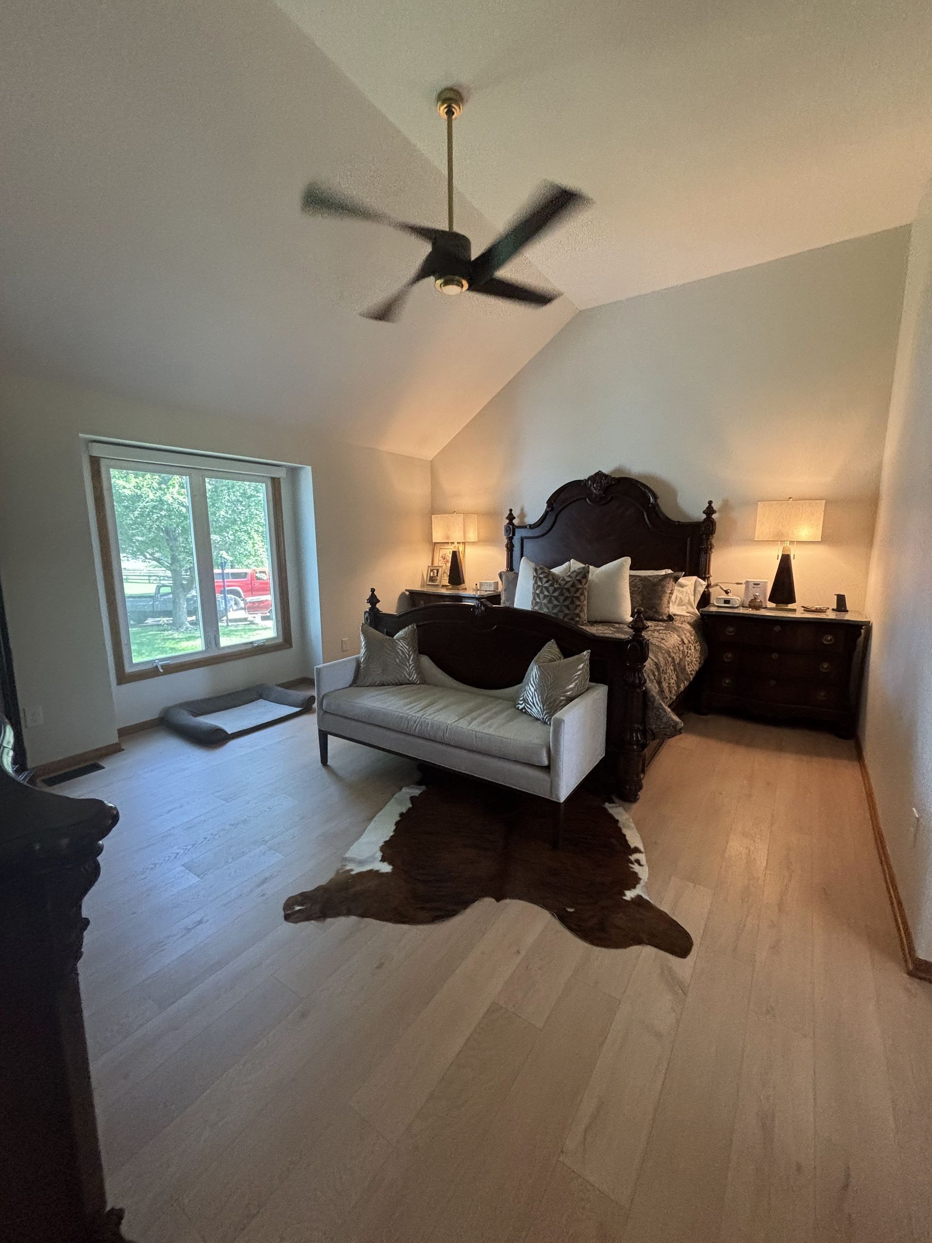 A bedroom with a bed, couch, and ceiling fan.