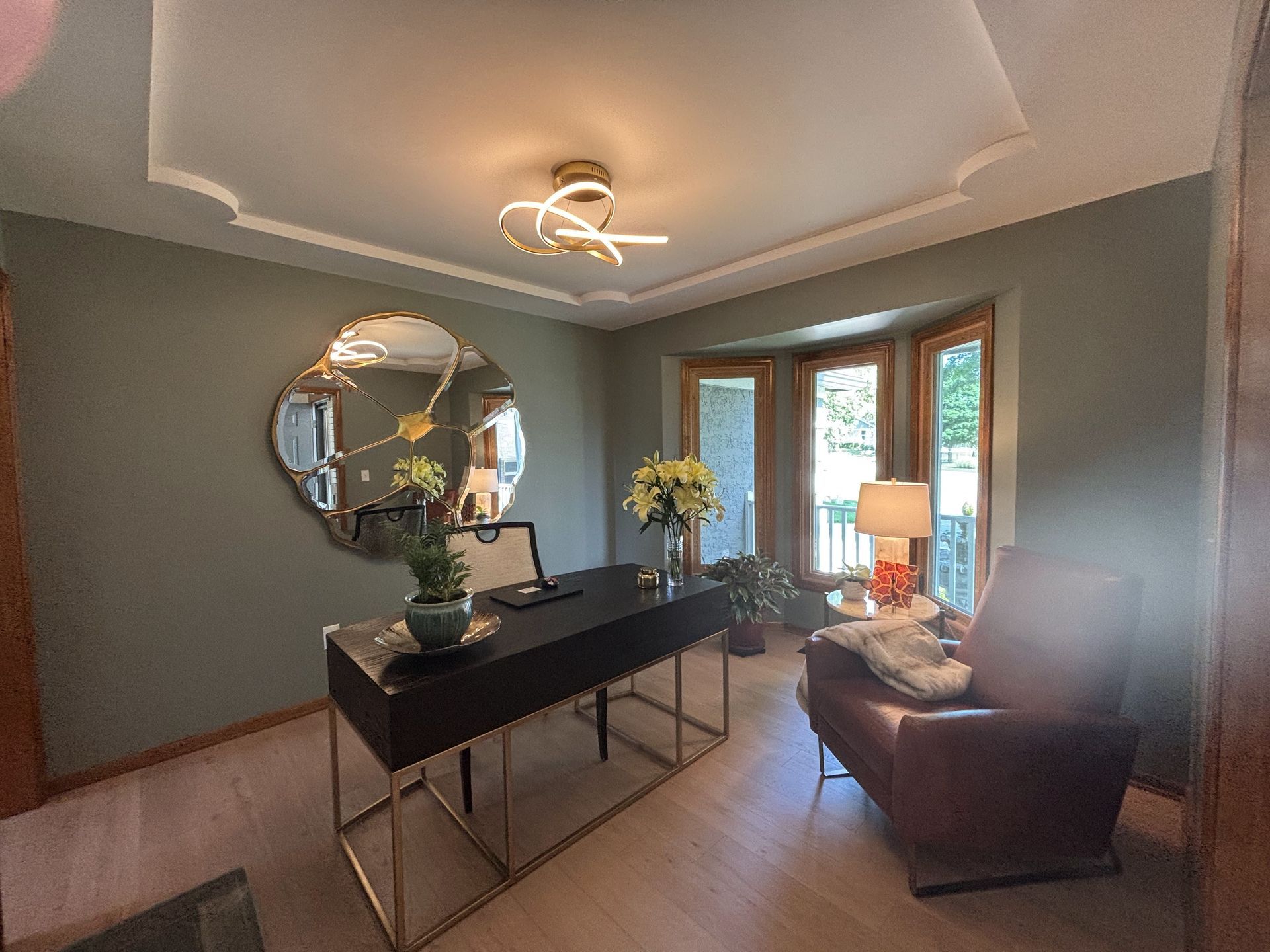 A living room with a desk, chairs, and a large mirror.
