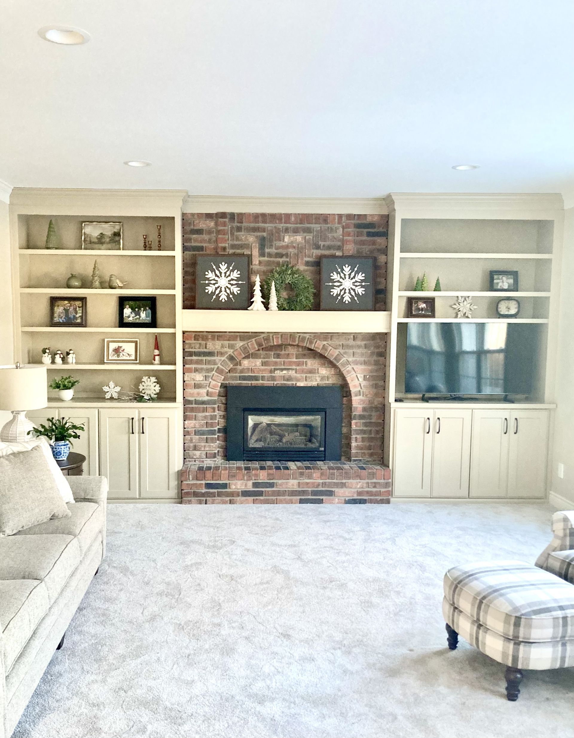 A living room with a brick fireplace and built in shelves.