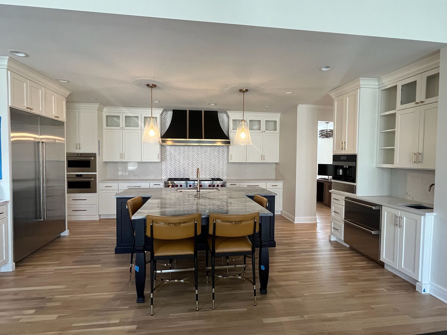 Bright modern kitchen with white cabinets, stainless appliances, island, and bar stools