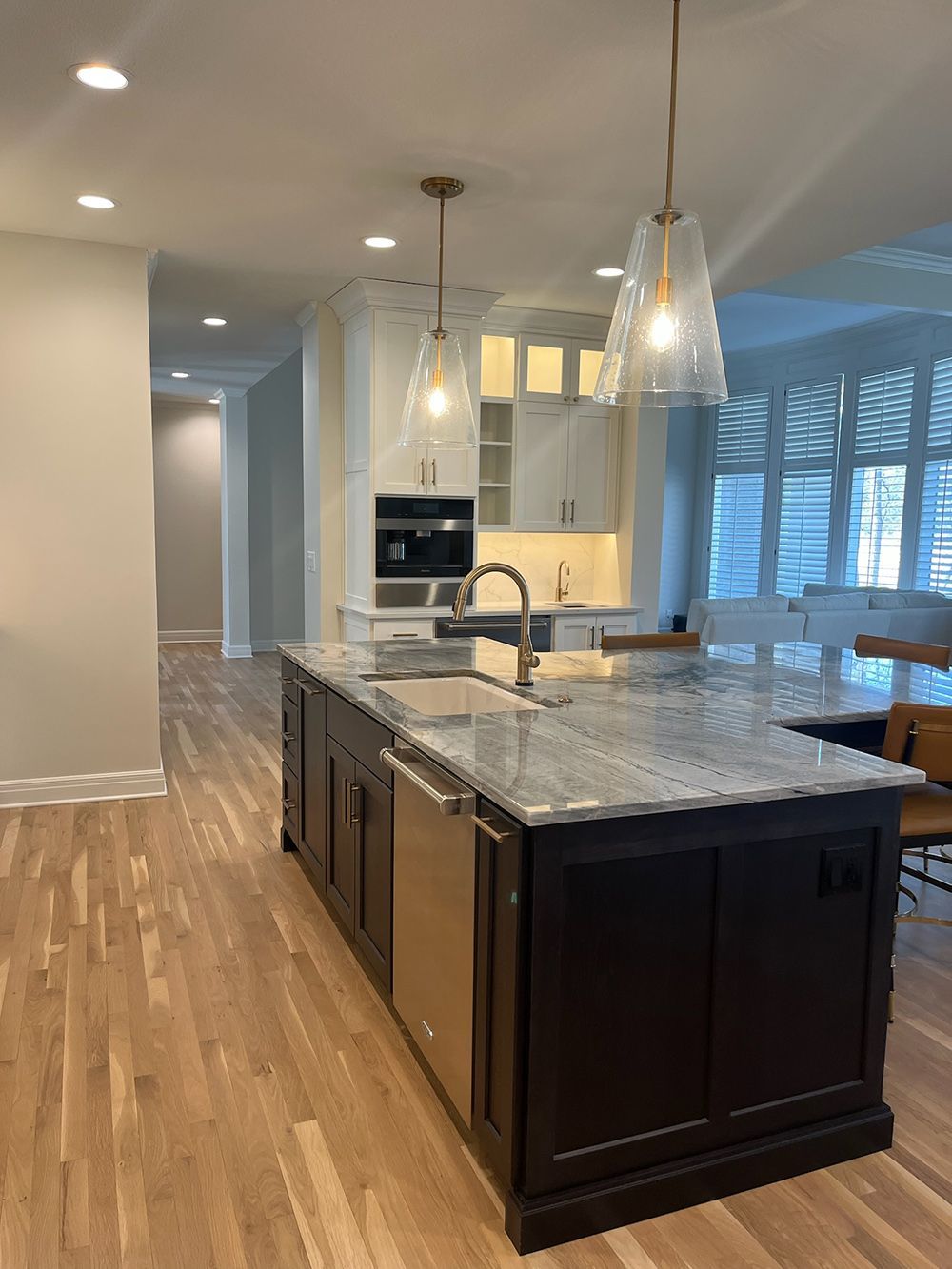 Modern kitchen with dark island, granite countertop, pendant lights, and hardwood floors