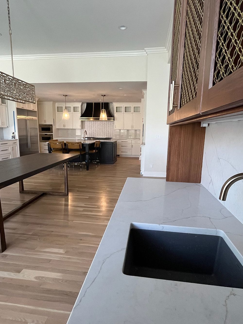 Open kitchen and living area with wood floors and gray countertops, viewed from a corner.