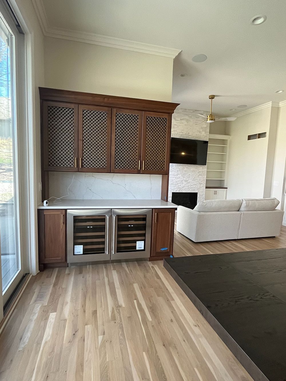 Modern living room with wood floor, built-in cabinet, wall-mounted TV, and a light-colored sofa.